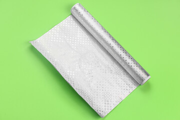 Roll of aluminium foil on green background