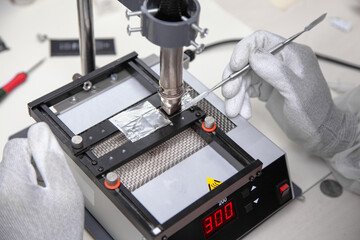 The master solders the microchip at the soldering station. Service center. Repair of microelectronics.