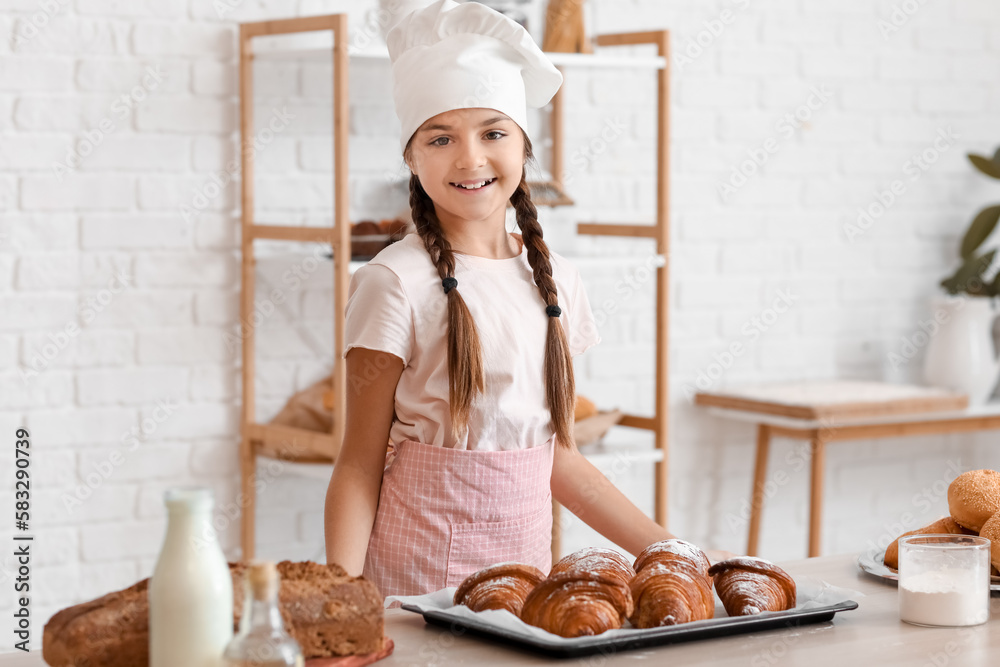 Sticker Little baker and tray with tasty croissants on table in kitchen