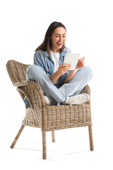Fototapeta na wymiar Young woman using tablet computer in wicker armchair on white background