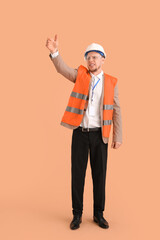 Male architect in vest pointing at something on beige background