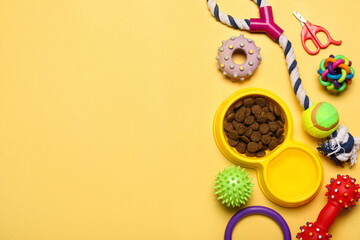 Bowl of dry pet food, nail clipper and toys on color background