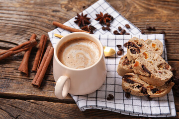 Delicious biscotti cookies, cinnamon, beans and cup of coffee on wooden background