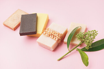 Set of natural soap bars and plant branch on pink background