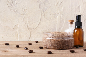Jar of body scrub, sea salt, essential oil and coffee beans on wooden table