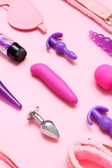 Different sex toys on pink background, closeup