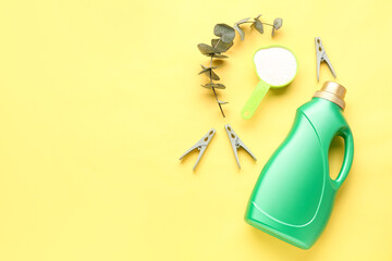 Laundry detergents, eucalyptus branch and clothespins on yellow background