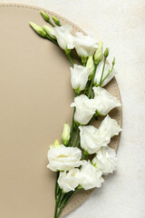 Composition with leather coaster and beautiful eustoma flowers on light background, closeup