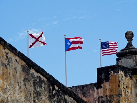 The Cross of Burgunday Flag, Flag of Puerto Rico and the United States Stars and Strips Flag fly at Castillo San Felipe del Morro in Old San Juan