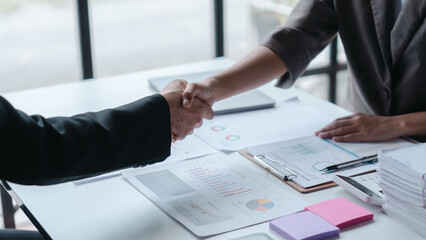 Shaking hands, Auditor and the company's bookkeeper jointly review the balance sheet and assets, liabilities and equity information in the quarterly report, bookkeeping concept.