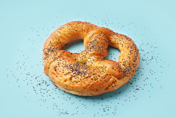 Tasty pretzel with poppy seeds on color background
