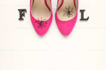 Word FOOL with female shoes and spiders on white wooden background