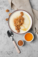 Bowl of tasty semolina porridge with nuts, cinnamon and honey on grunge background