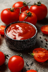 Bowl with tasty ketchup and fresh tomatoes on grunge background