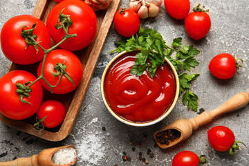 Bowl with tasty ketchup and fresh vegetables on grunge background