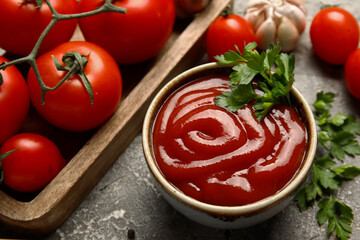 Bowl with tasty ketchup and fresh tomatoes on grunge background