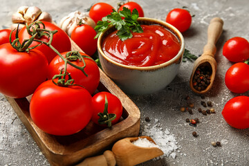 Bowl with tasty ketchup and fresh tomatoes on grunge background