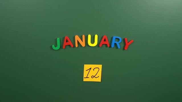 Hand sticking a sticker 12 January calendar day on school board. 12 date of January. Twelfth day of January. 12th date number. 12 day calendar. Twelve date