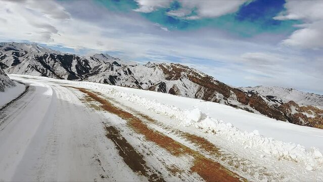 Car drives on snowy road winding in Caucasus mountains