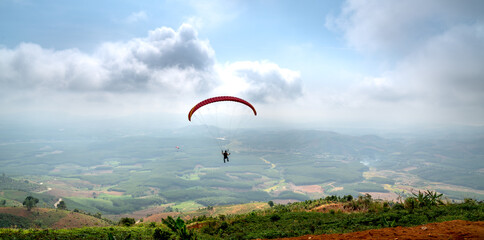 Paragliding on Chu Tan Kra mountain peak in Sa Thay district, Kon Tum province, Vietnam   - obrazy, fototapety, plakaty
