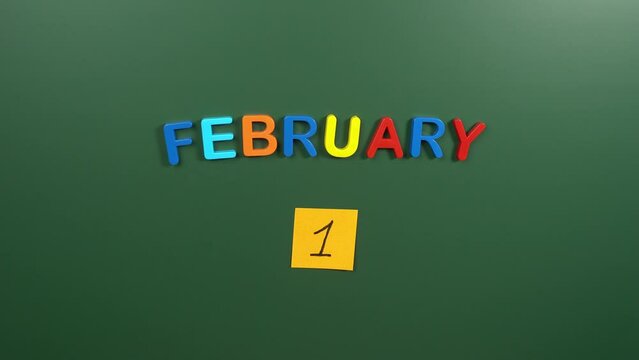 Hand sticking a sticker 1 February calendar day on school board. 1 date of February. First day of February. 1st date number. 1 day calendar. One date