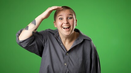 Portrait of happy smiling gender fluid non binary young woman 20s smiling and look around for friend find waving meet greet with hand as notices someone isolated on green screen background.