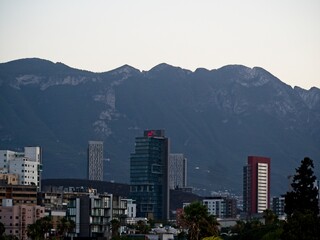 Obraz premium Towering high rises peek over the Loma Larga, a steep hill that divides the cities of Monterrey and San Pedro Garza García, with the Sierra Madre Oriental mountain range in the background
