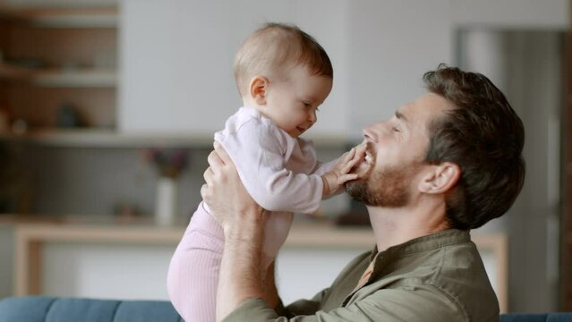 Unconditional father love. Happy father holding his lovely adorable baby daughter on hands, hugging and rubbing noses