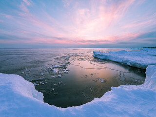 Shoreline of Lake Superior formed by snowbank in winter at sunset