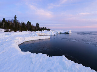 Shoreline of Lake Superior formed by snowbank in winter at sunset