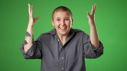 Pretty thinking non binary gender fluid young woman 20s, looks at camera gives mind blown gesture showing explosion of ideas posing on green screen background.