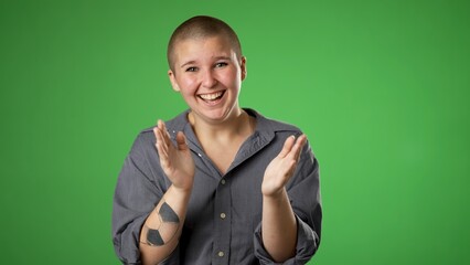 Portrait of non binary gender fluid woman 20s looks at camera rejoices clapping hands applause...