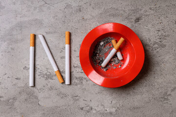 No Smoking sign made with cigarettes and red ashtray on rustic grey background. World No Tobacco Day concept.