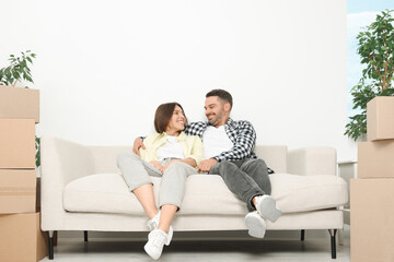 Happy couple resting on sofa in new apartment. Moving day
