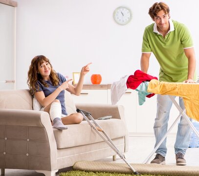 Husband helping leg injured wife in housework