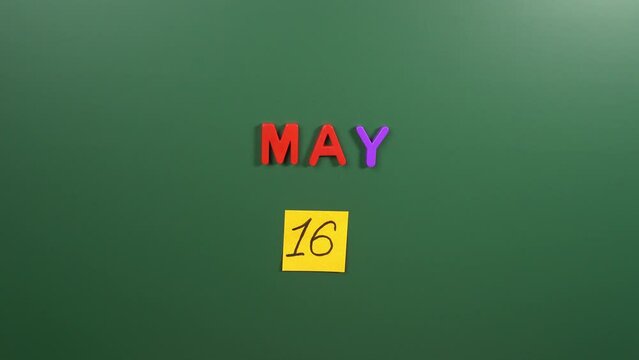 Hand sticking a sticker 16 May calendar day on school board. 16 date of May. Sixteenth day of May. 16th date number. 16 day calendar. Sixteen date. International of Living Together in Peace