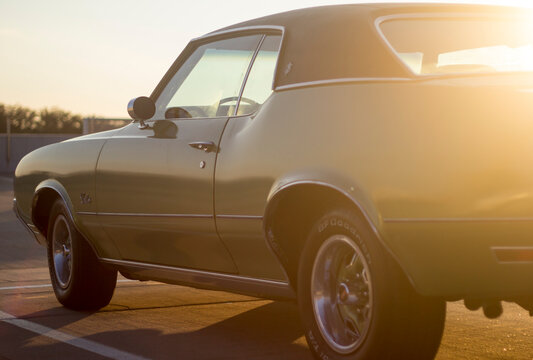 Fototapeta Green vintage muscle car with sunset lighting