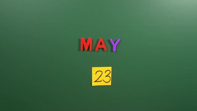 Hand sticking a sticker 23 May calendar day on school board. 23 date of May. Twenty third day of May. 23th date number. 23 day calendar. Twenty three date. World Turtle