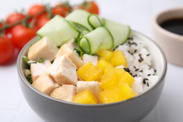 Delicious poke bowl with meat, rice and vegetables on white table, closeup