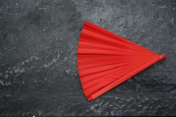 Bright red hand fan on grey textured background, top view. Space for text