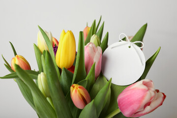 Bouquet of colorful tulips with blank card on white background, closeup