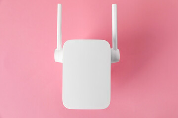 New modern Wi-Fi repeater on pink background, top view