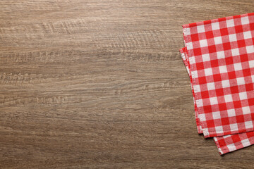 Obraz premium Checkered tablecloth on wooden table, top view. Space for text