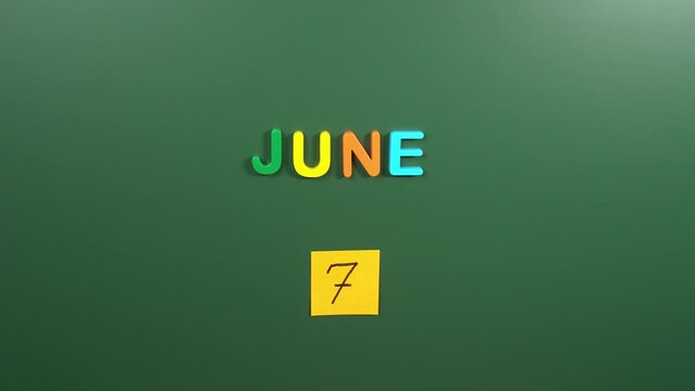 Hand sticking a sticker 7 June calendar day on school board. 7 date of June. Seventh day of June. 7th date number. 7 day calendar. Seven date. World Food Safety