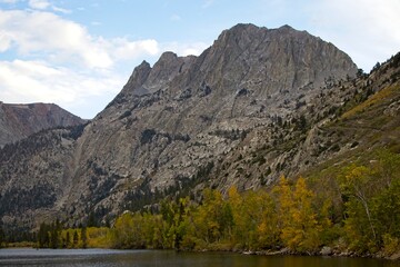 Driving through June Lake loop in the Eastern Sierra, where towering mountains loom overhead and fall colors begin to show on some of the trees at their base. Seen here is Grant Lake.