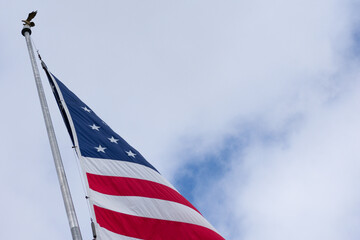 The American Flag on a flag pole against a cloudy sky
