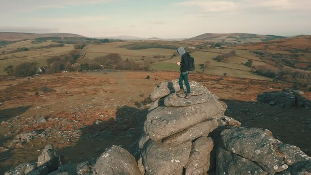Drone pilot standing on top of a rock formation in national park landscape