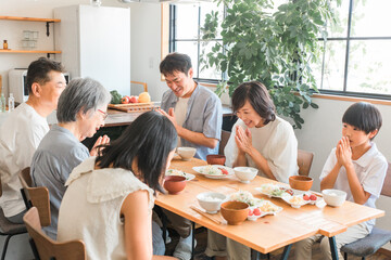 Obraz premium 家のダイニングで家族団欒して食事する子供と夫婦・親子・三世代家族（二世帯住宅・里帰り・帰省） 