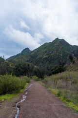 Malibu Creek State Park muddy after a large rainfall in southern California. Streams overflowing, lush green grass, large oak trees, clouds, dam rushing, water flowing.