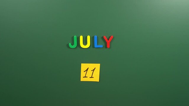 Hand sticking a sticker 11 July calendar day on school board. 11 date of July. Eleventh day of July. 11th date number. 11 day calendar. Eleven date. Population, American Pet Photo, Essential Oils